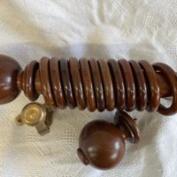 Antique mahogany pole with finials, brackets and rings.